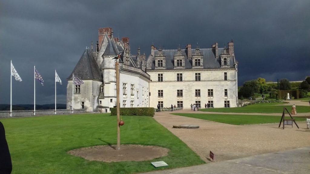 Château d'Amboise avec cour intérieur et drapeaux sur le côté gauche. Ciel menaçant