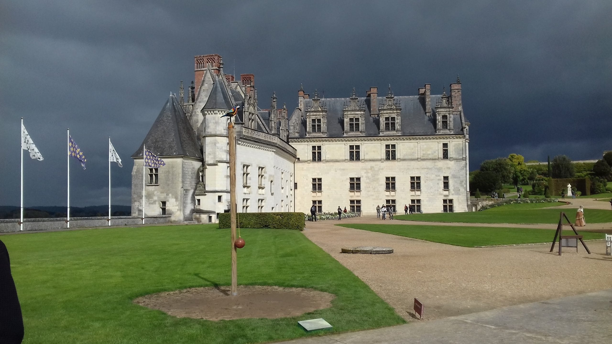 Château d'Amboise avec cour intérieur et drapeaux sur le côté gauche. Ciel menaçant