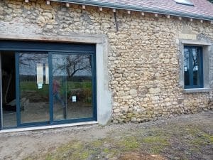 fenêtre et baie vitrée avec mur en pierres apparentes en attente d'un enduit