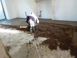carreleur de dos en train de poser une chappe de béton
