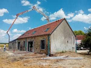 Vue-arrière-de-la-maison-avec-une-toupie-versant-du-béton-pour-couler-des-terrasses-en-passant-au-dessus-du-toit