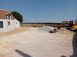 Tas-de-gravier-dans-la-cour avec pelleteuse et rouleau compresseur qui aplati