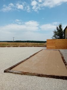 terrain de pétanque entouré de petites pierres blanches avec vue sur les champs
