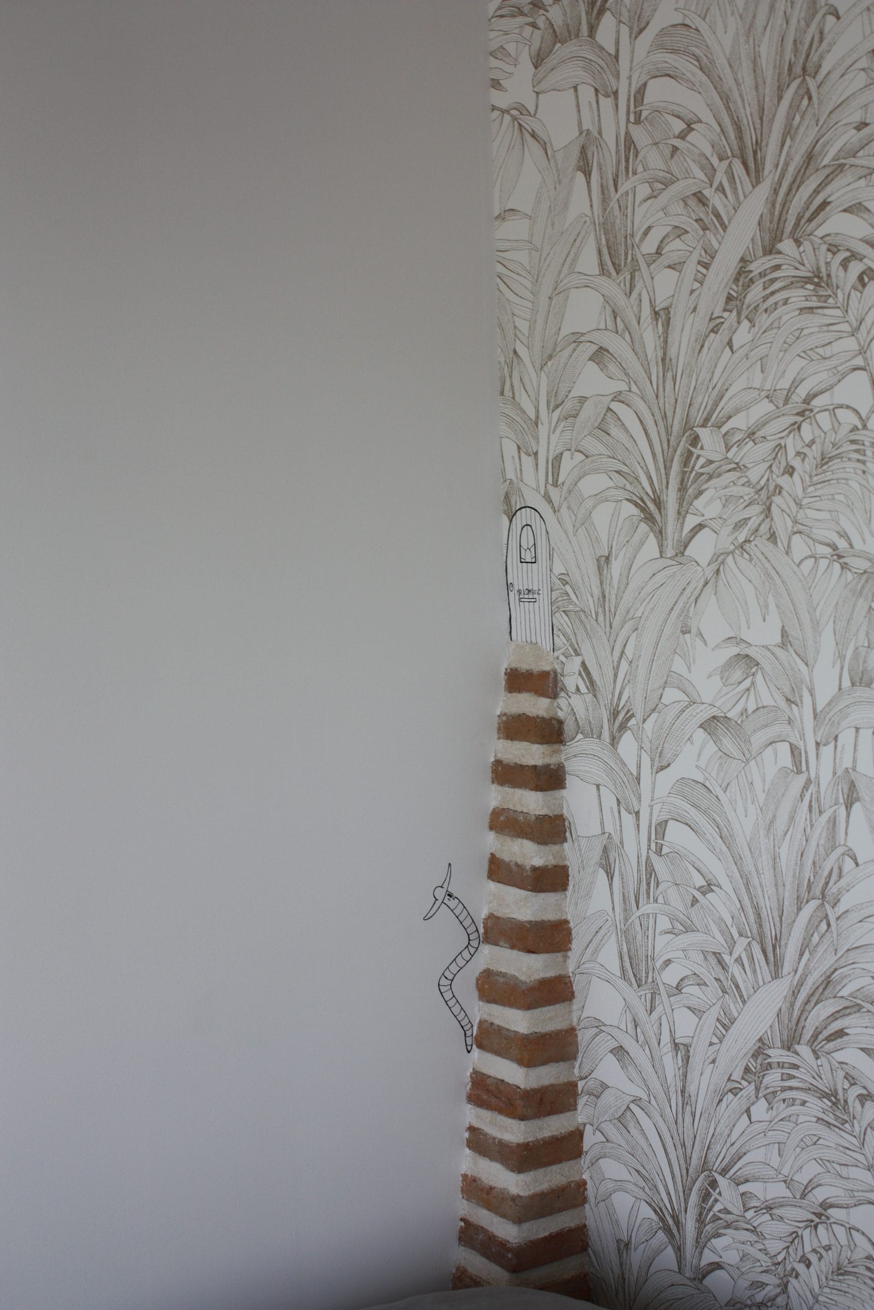 décoration-murale-faite-à-la-main-représentant-un-petit-lombric-humoristique-grimpant-une-petite-partie-de-la-cheminée-en-brique-pour-rentrer-dans-sa-maison