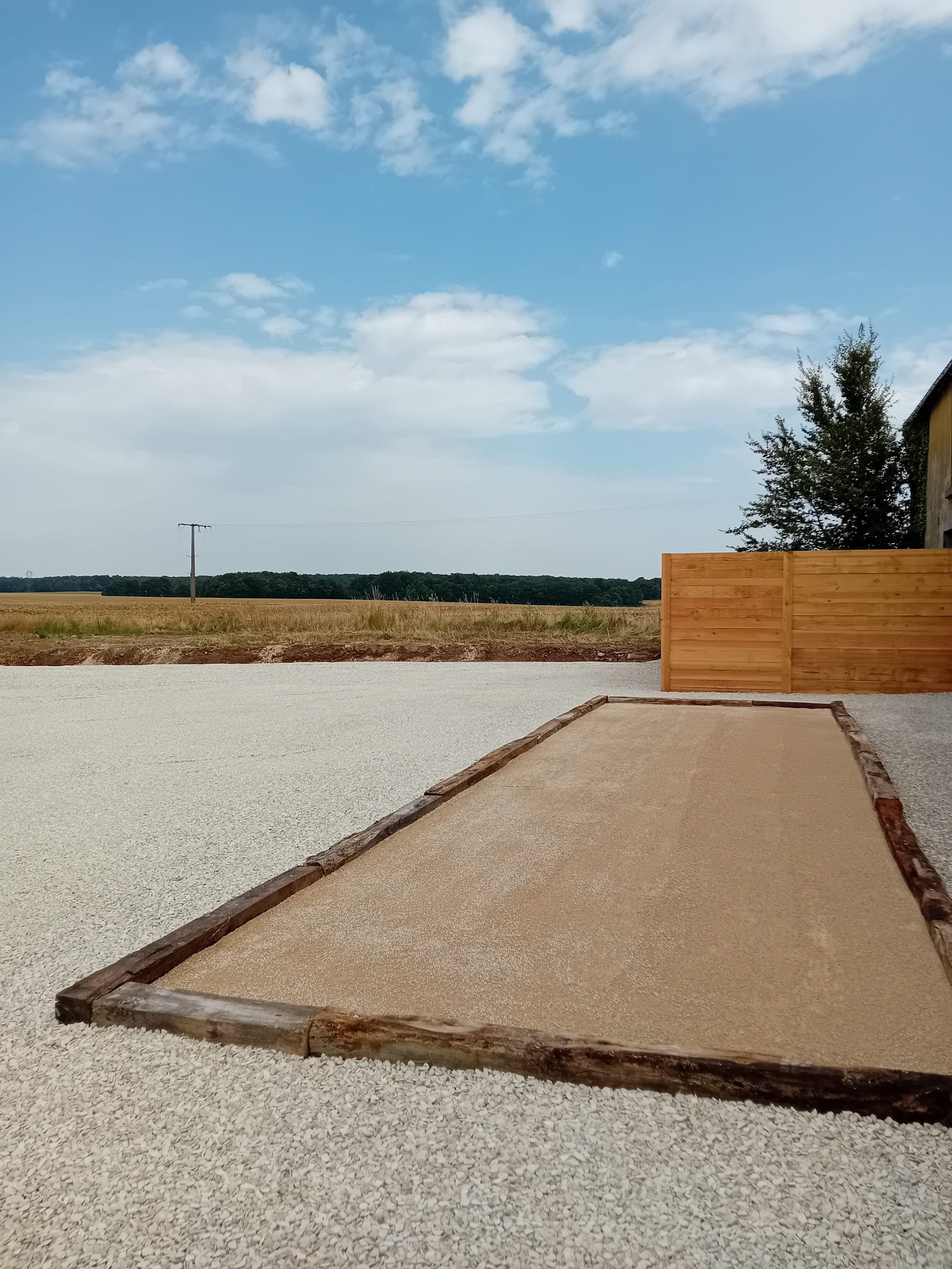 terrain de pétanque entouré de petites pierres blanches avec vue sur les champs