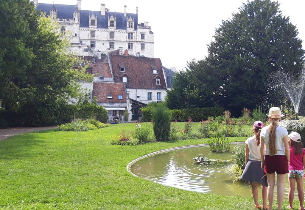Château de Loches en arrière plan avec de la verdure devant et une petite fontaine avec des enfants