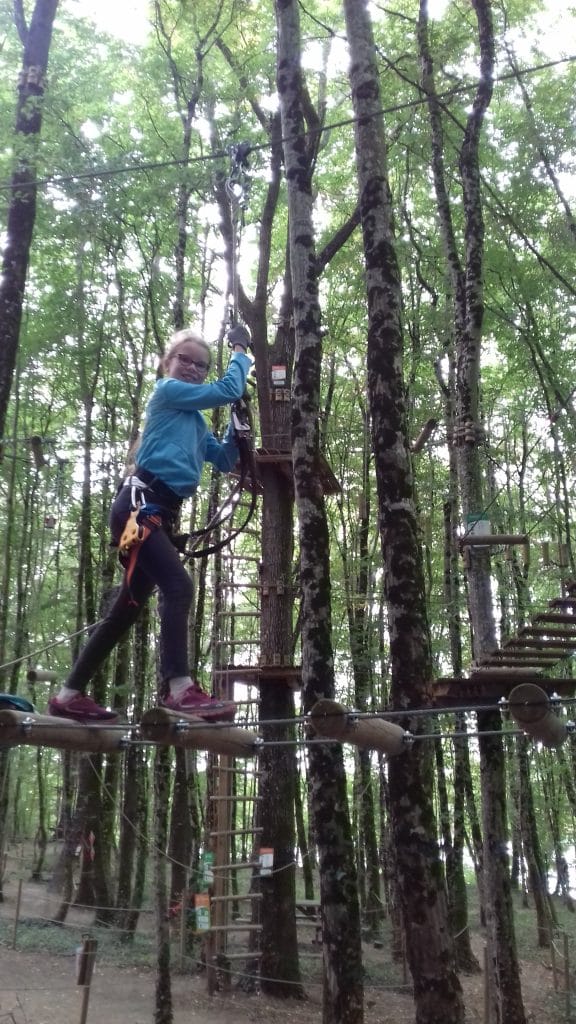 jeune fille passant d'un rondin à l'autre en haut des arbres