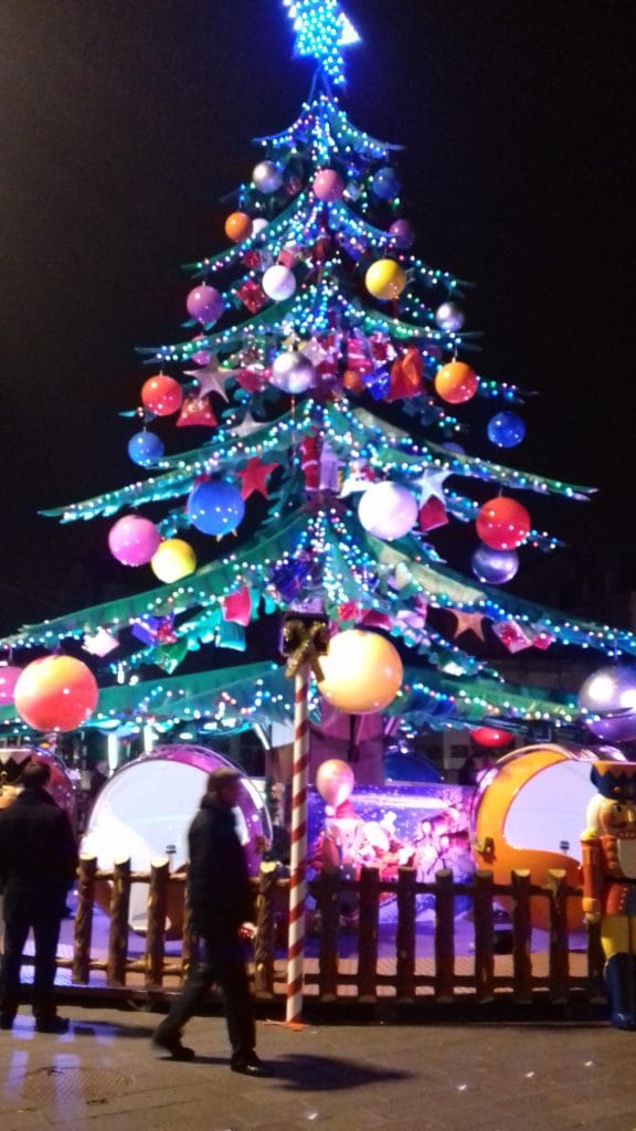 Manège illuminé en forme de sapin de Noël, les boules servant de siège pour les passagers