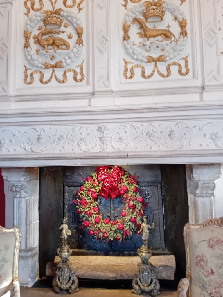 Couronne de noël verte et rouge accrochée dans une cheminée en pierre du château de Chenonceau