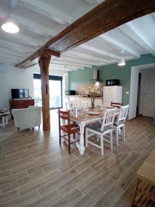 pièce avec table et chaises blanches carrelage imitation bois en arrière plan cuisine blanche avec mur vert