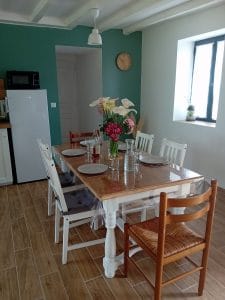 cuisine avec une table et six chaises un bouquet de fleur au centre de la table avec le couvert mis