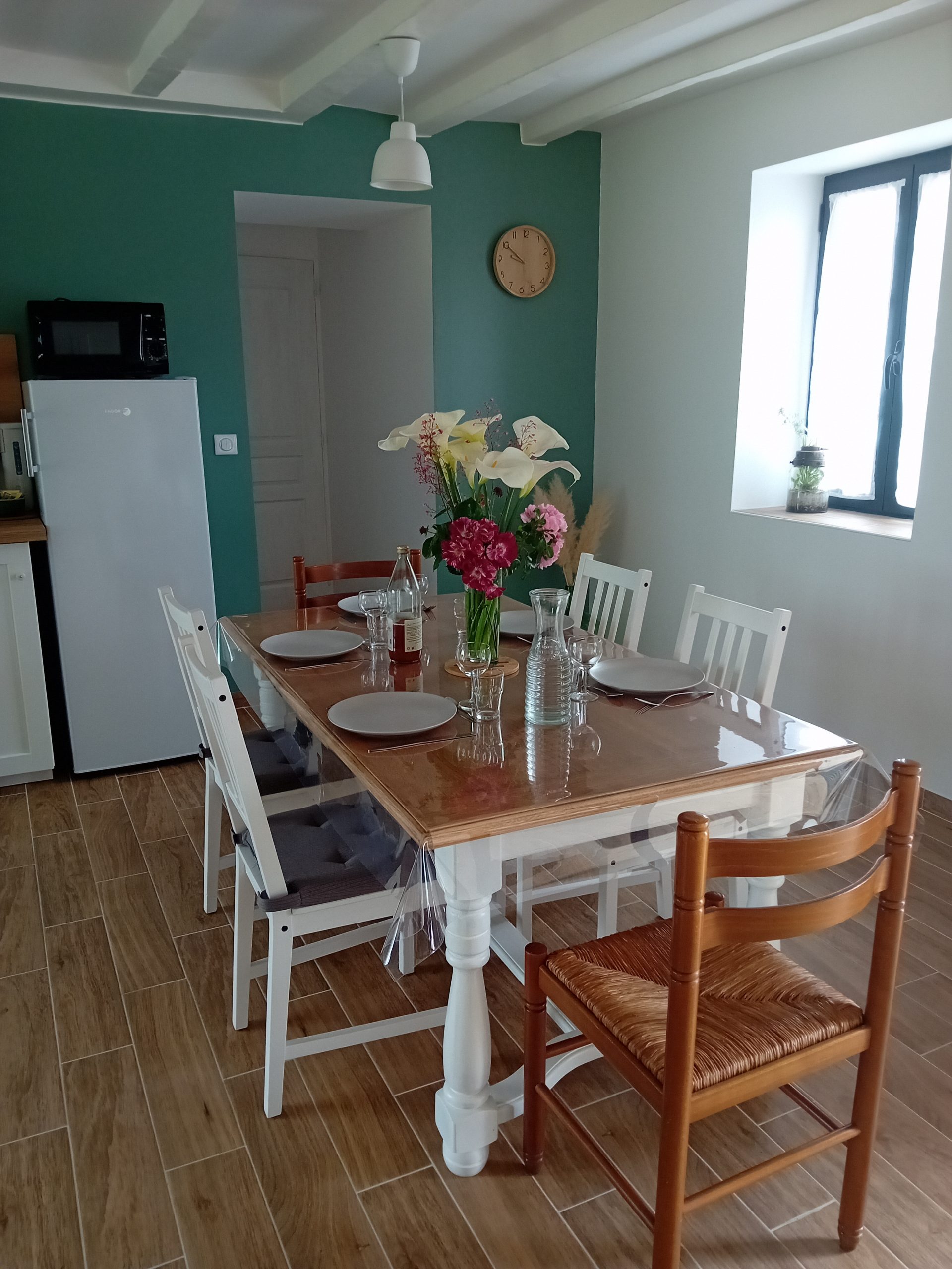 cuisine avec une table et six chaises un bouquet de fleur au centre de la table avec le couvert mis